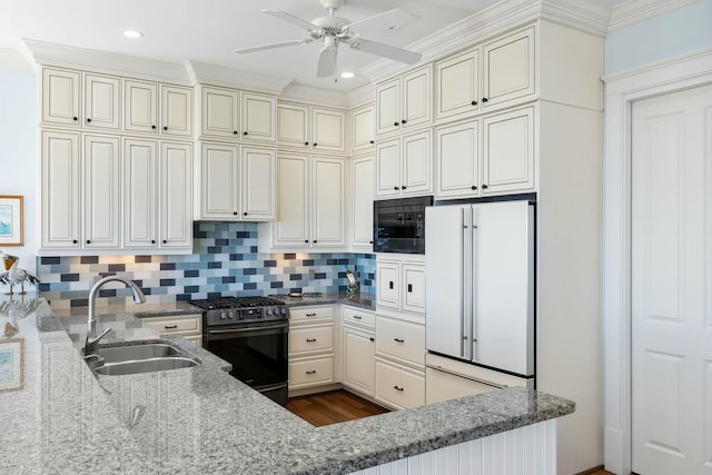 kitchen featuring backsplash, stainless steel range with gas cooktop, black microwave, freestanding refrigerator, and a sink