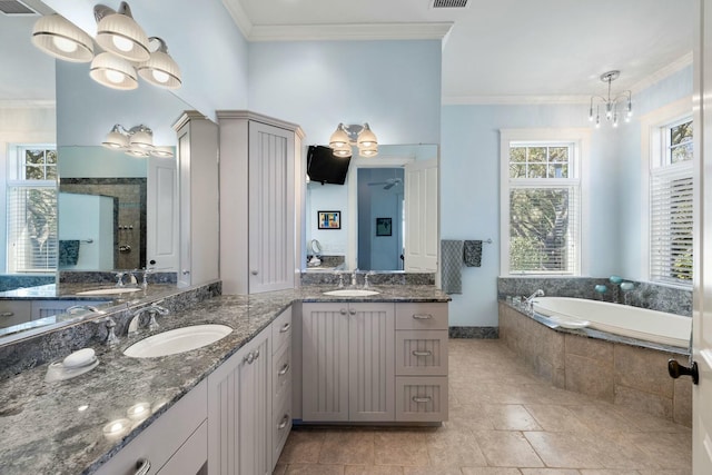 bathroom featuring an inviting chandelier, crown molding, a garden tub, and a sink