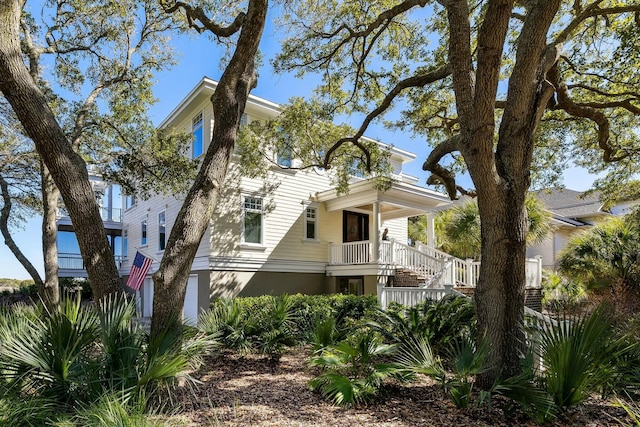 view of front of house with stairway, covered porch, and stucco siding