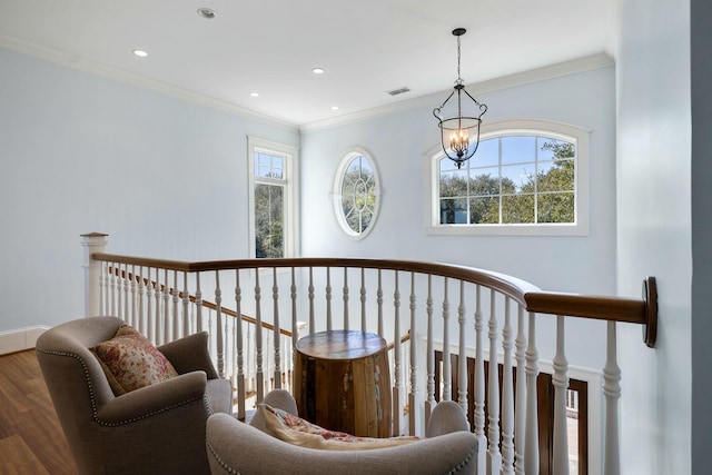 hallway with visible vents, an upstairs landing, ornamental molding, wood finished floors, and a chandelier