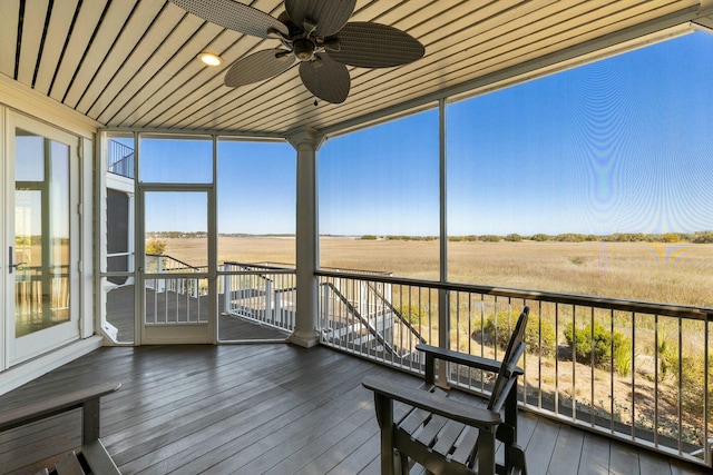 unfurnished sunroom featuring a ceiling fan and a rural view