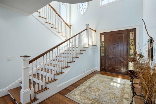 entryway featuring stairway, a high ceiling, baseboards, and wood finished floors