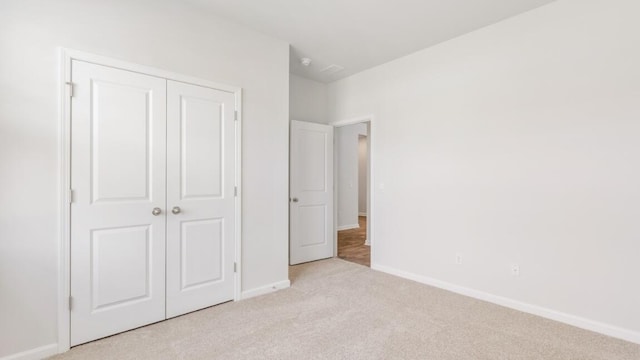 unfurnished bedroom featuring light colored carpet and a closet