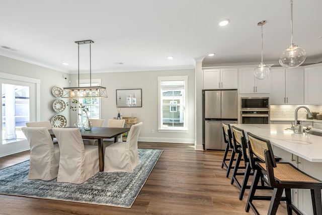 dining space featuring dark wood-type flooring, plenty of natural light, and ornamental molding