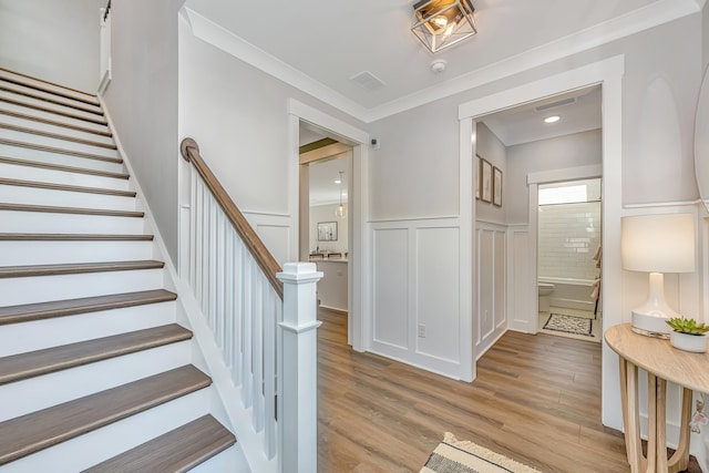 staircase featuring light wood-type flooring and crown molding