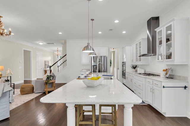 kitchen featuring pendant lighting, wall chimney range hood, sink, a large island, and stainless steel appliances