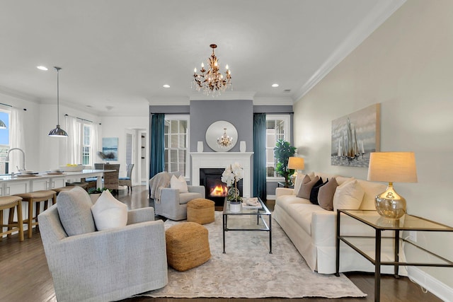 living room with crown molding, sink, a chandelier, and hardwood / wood-style flooring