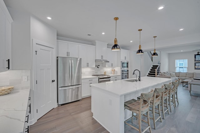 445 Oswego Ct, Greenville, SC 29607 - kitchen with appliances with stainless steel finishes, a sink, under cabinet range hood, light wood finished floors, and open floor plan
