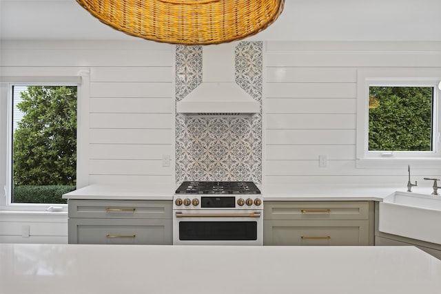 1075 Wayfarer Ln, Charleston, SC 29412 - kitchen with white gas range oven, gray cabinets, light countertops, premium range hood, and decorative backsplash