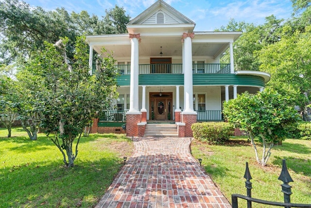 greek revival inspired property featuring a front lawn, a balcony, and a porch