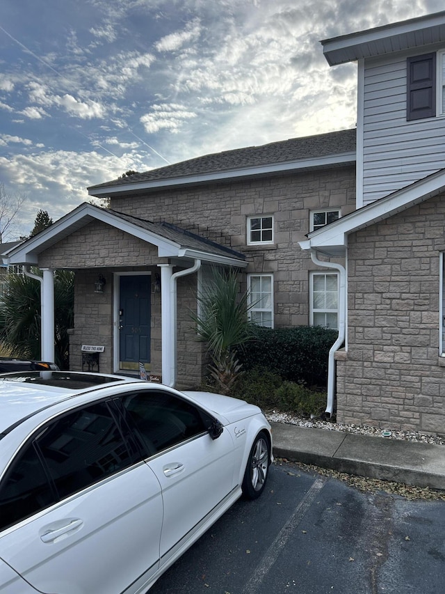 view of front of home with uncovered parking and stone siding