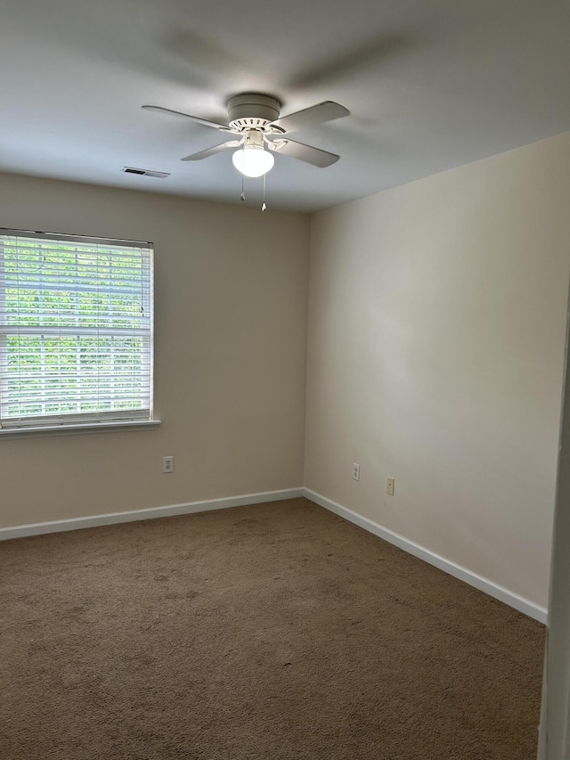 carpeted spare room featuring ceiling fan, visible vents, and baseboards