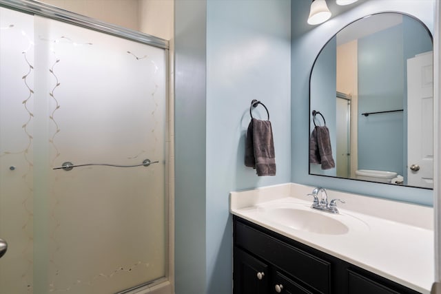 full bathroom with vanity, toilet, and a shower with shower door