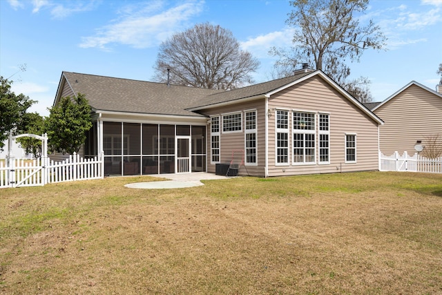 back of house with a lawn, a fenced backyard, a sunroom, and a chimney