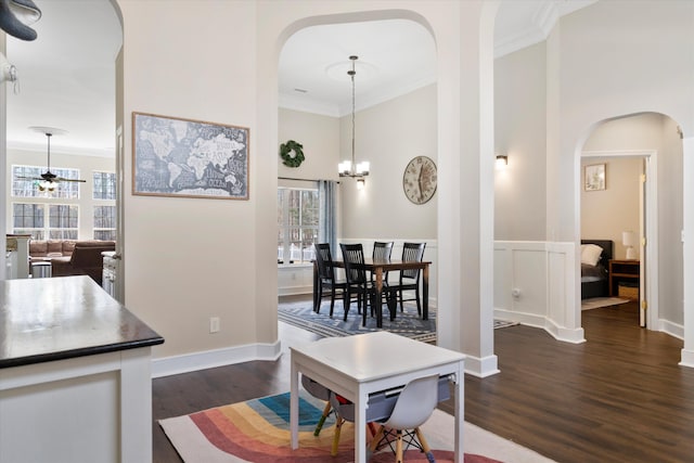 dining space with a wainscoted wall, ornamental molding, arched walkways, a high ceiling, and dark wood-style flooring