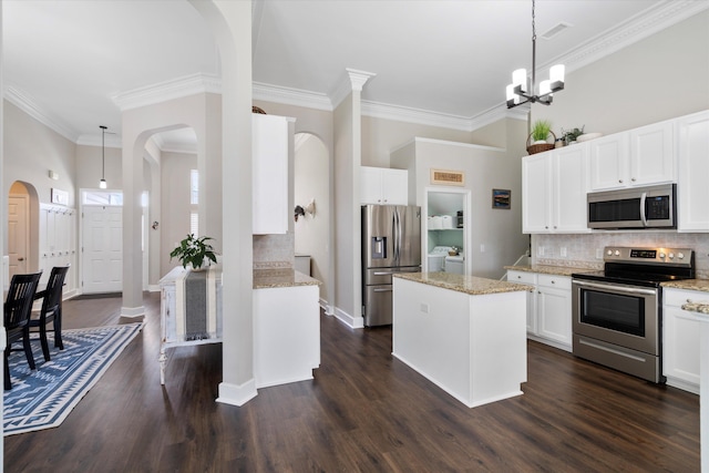 kitchen with dark wood-style floors, arched walkways, stainless steel appliances, backsplash, and a center island