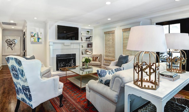 living area featuring built in shelves, a fireplace, wood finished floors, and crown molding