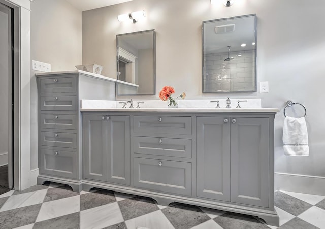 bathroom with double vanity, visible vents, a tile shower, and a sink