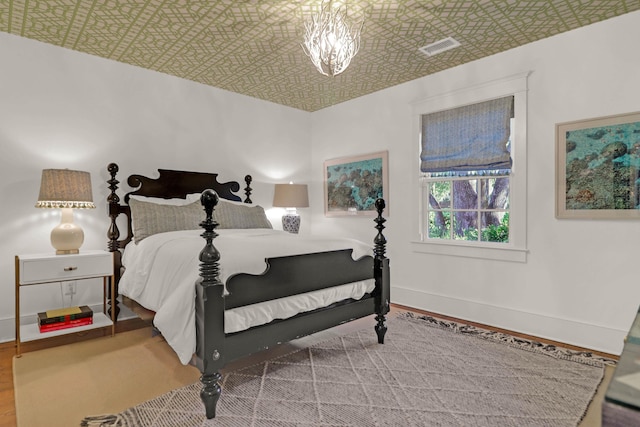 bedroom featuring visible vents, wood finished floors, baseboards, and an ornate ceiling