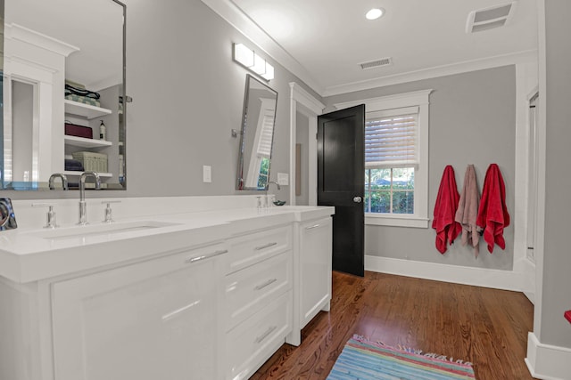 bathroom featuring visible vents, ornamental molding, wood finished floors, and a sink