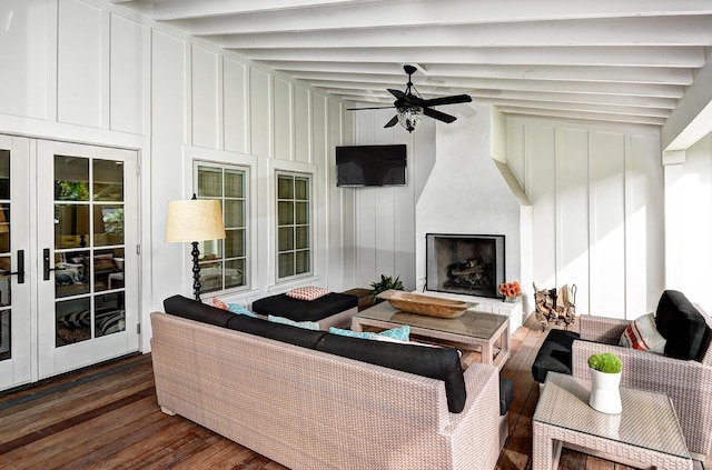 living room with dark wood-type flooring, ceiling fan, lofted ceiling with beams, a fireplace, and a decorative wall