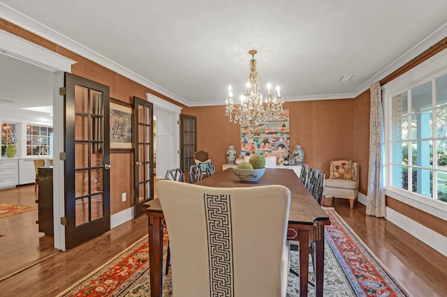 dining area featuring a chandelier, french doors, wood finished floors, and ornamental molding