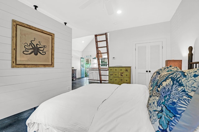 bedroom featuring a closet, wooden walls, a ceiling fan, and lofted ceiling