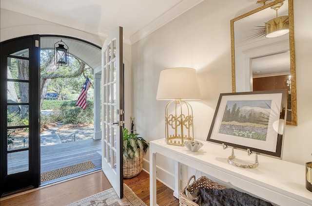 foyer featuring crown molding, wood finished floors, arched walkways, and french doors