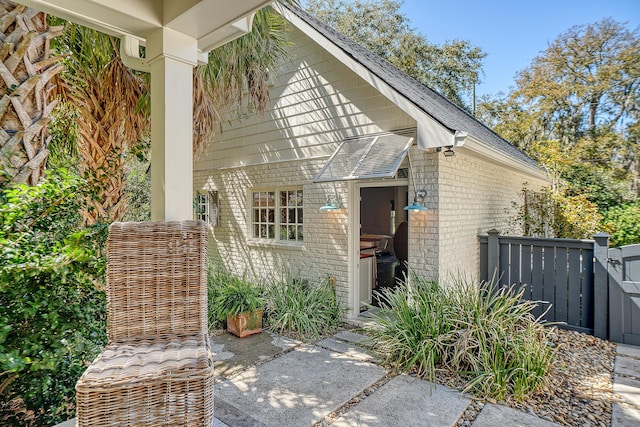 exterior space with fence, brick siding, and a shingled roof