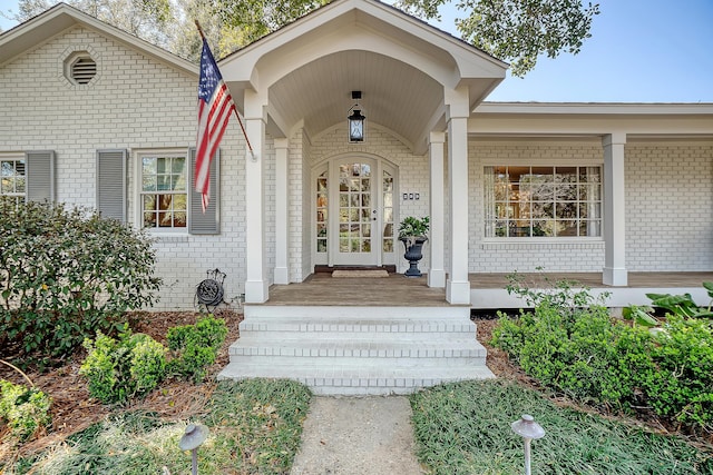doorway to property with covered porch and brick siding