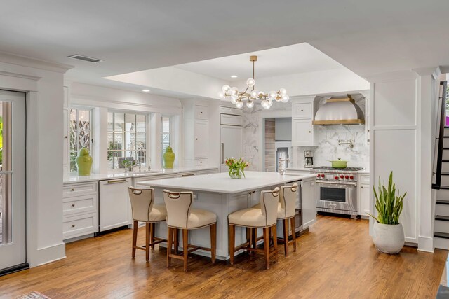 kitchen featuring visible vents, premium stove, light countertops, white dishwasher, and white cabinetry