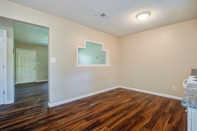 unfurnished room featuring dark wood-type flooring and a textured ceiling