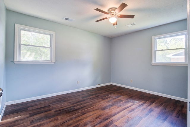 spare room featuring a wealth of natural light, ceiling fan, and dark hardwood / wood-style flooring