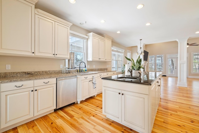 kitchen with ornate columns, dishwasher, sink, and light hardwood / wood-style floors