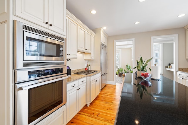 kitchen with built in appliances, white cabinets, and light wood-type flooring