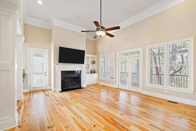 unfurnished living room featuring crown molding, ceiling fan, plenty of natural light, and light hardwood / wood-style floors