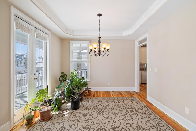 interior space featuring plenty of natural light, a raised ceiling, and a notable chandelier