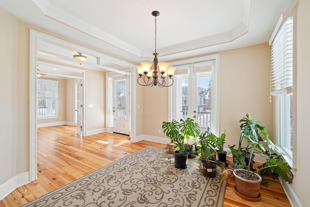 interior space with a tray ceiling, ornamental molding, light hardwood / wood-style floors, and a chandelier