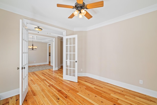 empty room with crown molding, hardwood / wood-style flooring, ceiling fan with notable chandelier, and french doors