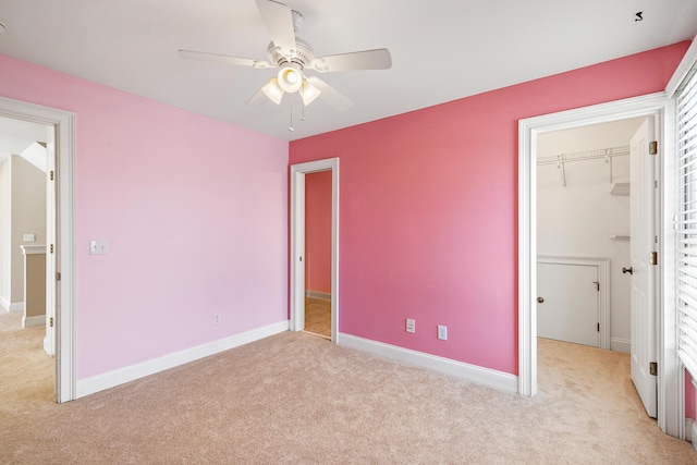 unfurnished bedroom featuring a spacious closet, light colored carpet, ceiling fan, and a closet