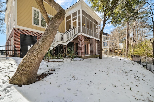 snow covered property featuring a sunroom