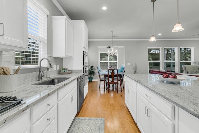 kitchen with light hardwood / wood-style flooring, sink, white cabinetry, pendant lighting, and stainless steel appliances