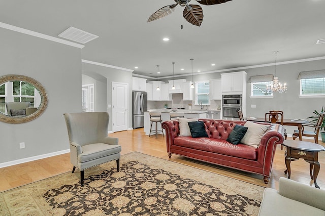 living room with ceiling fan with notable chandelier, light wood-type flooring, sink, and ornamental molding