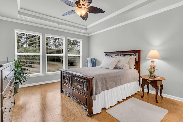 bedroom featuring a tray ceiling, ornamental molding, light wood-type flooring, and ceiling fan