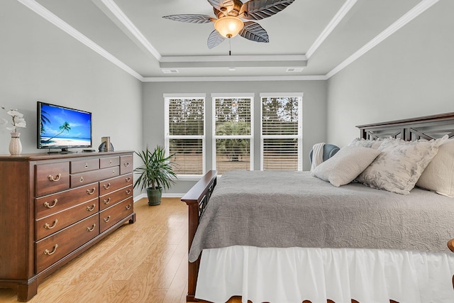 bedroom featuring ceiling fan, light hardwood / wood-style floors, crown molding, and a raised ceiling