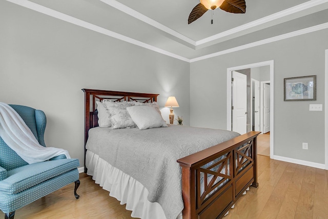 bedroom featuring a tray ceiling, ornamental molding, ceiling fan, and light hardwood / wood-style floors