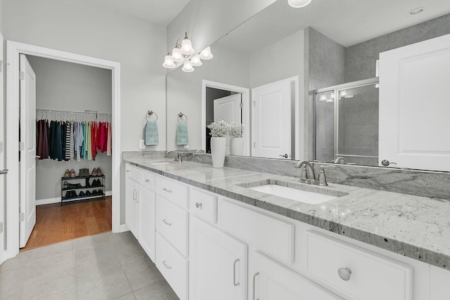 bathroom featuring tile patterned floors, vanity, an enclosed shower, and a notable chandelier