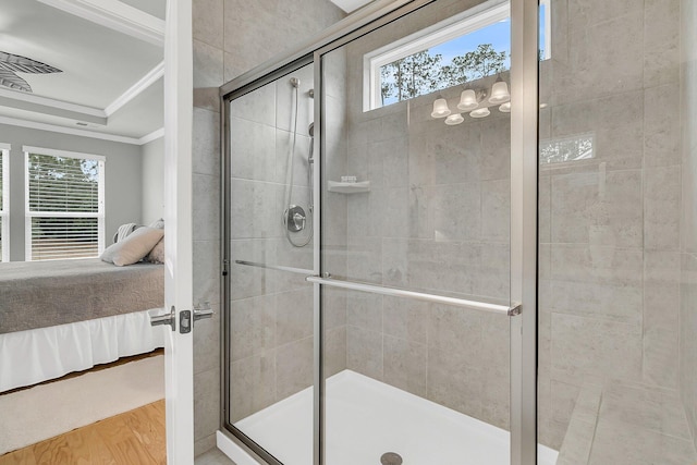 bathroom featuring crown molding, wood-type flooring, a shower with shower door, and a healthy amount of sunlight