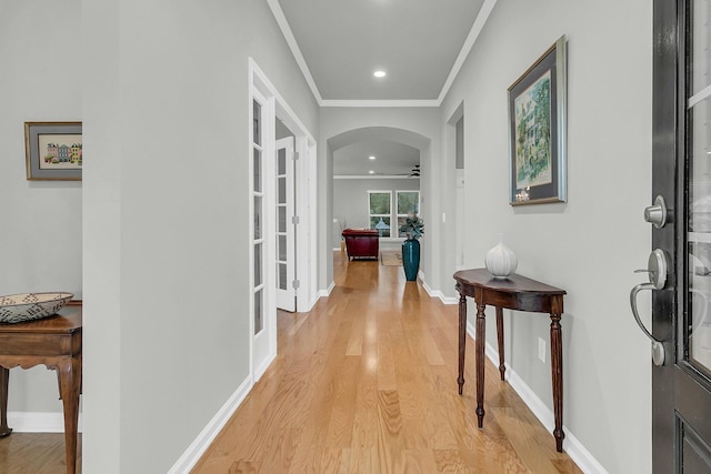 hallway with light wood-type flooring and ornamental molding