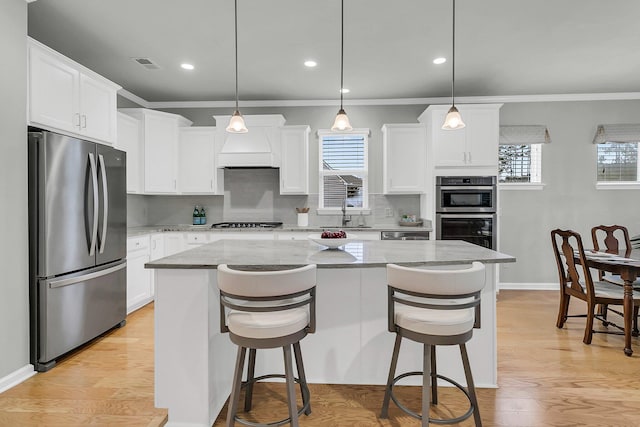 kitchen with stainless steel appliances, white cabinetry, hanging light fixtures, and a center island